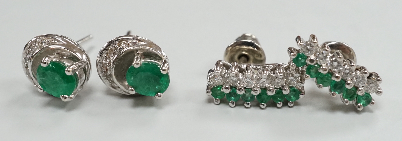 Two moderns pairs of emerald and diamond set ear studs, including white metal two row and 14k oval cut single stone and diamond chip, 7mm, gross weight 5.6 grams.